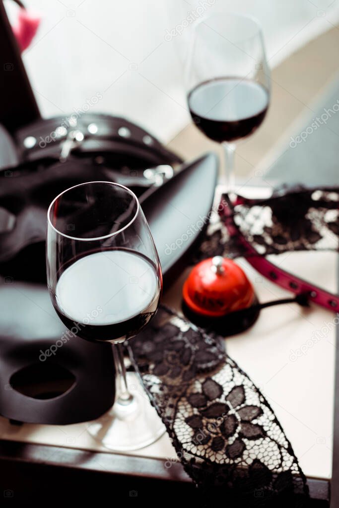 selective focus of rabbit mask near kiss bell and red wine in glasses