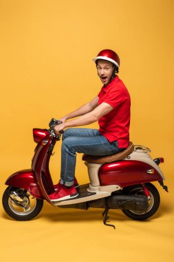 Sarı arka planda scooterlı heyecanlı teslimatçının yan görüntüsü