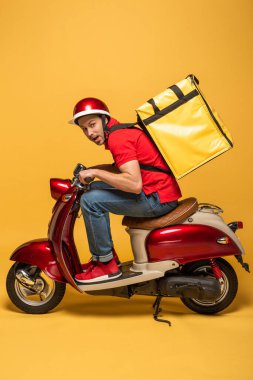 Sırt çantalı, motosikletli, sarı arka planlı teslimatçının yan görüntüsü