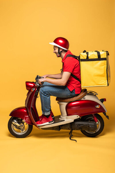 side view of delivery man with backpack on scooter on yellow background