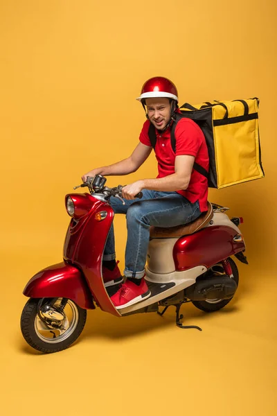 delivery man with backpack on scooter on yellow background