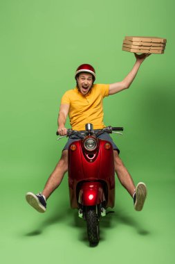 mad delivery man in yellow uniform on scooter delivering pizza on green