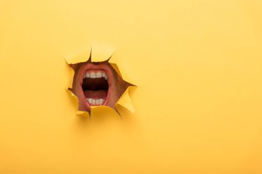 cropped view of open mouth in yellow paper hole  clipart