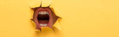 cropped view of open mouth in yellow paper hole  clipart