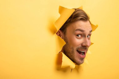 crazy handsome man with head in yellow paper hole 