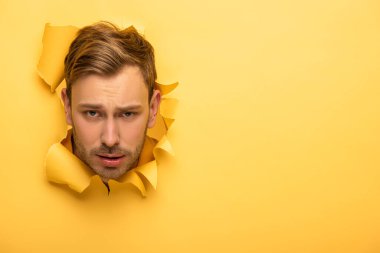 Sarı kağıt delikteki üzgün, yakışıklı adam. 