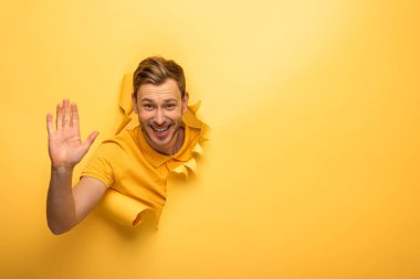 happy handsome man in yellow outfit in yellow paper hole giving high five clipart