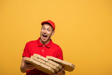 Kırmızı üniformalı ürkek teslimatçı pizza kutularını bırakıyor ve sarı üzerine izole bir şekilde bağırıyor.