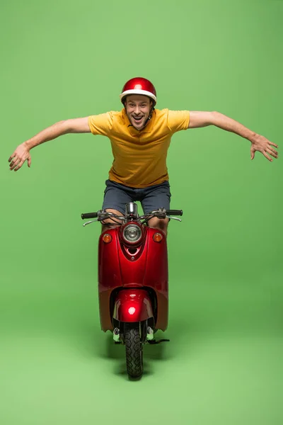 Homem Entrega Feliz Uniforme Amarelo Capacete Fazendo Truque Scooter Verde — Fotografia de Stock