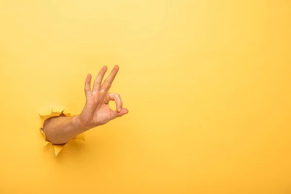 Vista Cortada Homem Mostrando Sinal Através Buraco Papel Amarelo — Fotografia de Stock