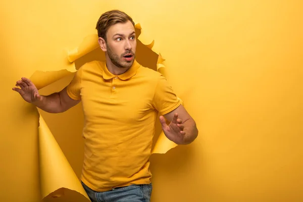 Verrast Knappe Man Gele Outfit Lopen Door Geel Papieren Gat — Stockfoto