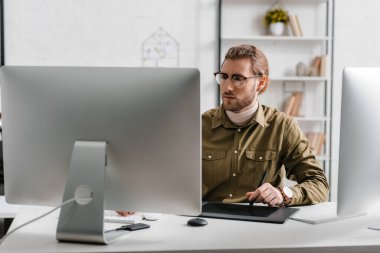 Ofisteki masada bilgisayar ve grafik tableti kullanan dijital tasarımcı 