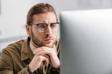 Ofisteki bilgisayar monitörüne bakan düşünceli 3D ressamın seçici odağı 
