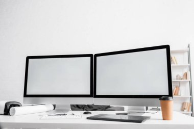 Bilgisayarlar, kahve tabletleri ve ofis masasındaki kulaklıklar. 