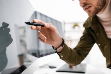Ofisinde siyah ekran olan bilgisayar monitörünün yanında grafik tabletinin stilini tutan 3D sanatçının seçici odağı