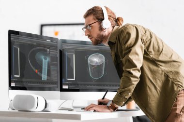 3D kulaklıklı bir sanatçının yan görüntüsü VR kulaklık yanında 3D tasarım projesi üzerinde çalışıyor.