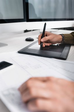 Tablonun yanında çalışırken grafik tableti kullanan 3D ressamın seçici odak noktası