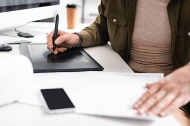 Tablet, bilgisayar ve planla çalışan dijital tasarımcının seçici odak noktası