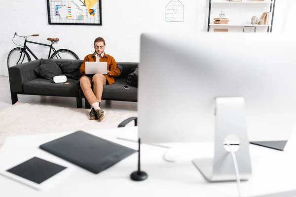 オフィスでソファの上にVrヘッドセットとスマートフォンの近くのノートパソコンを使用してデジタルデザイナーの選択的な焦点 — ストック写真