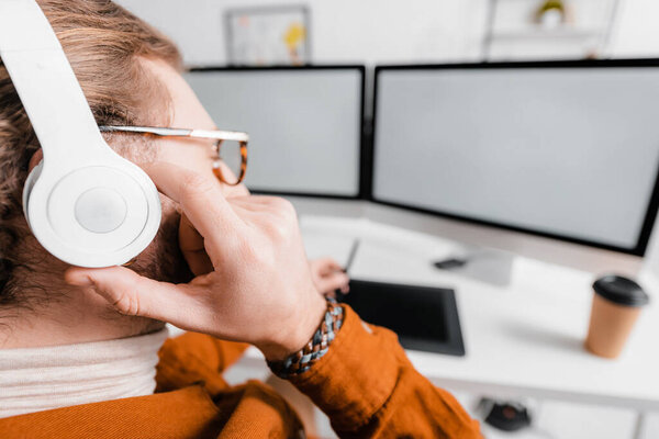 Selective focus of 3d artist listening music while rendering project on computers in office
