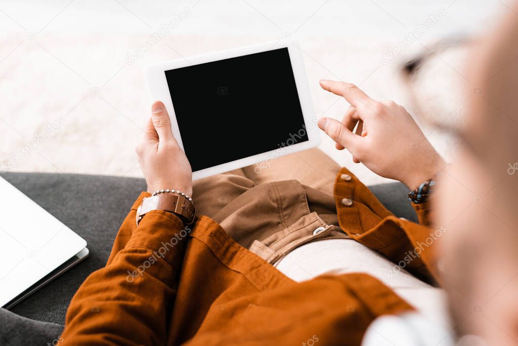 Selective focus of 3d artist using digital tablet near laptop on couch