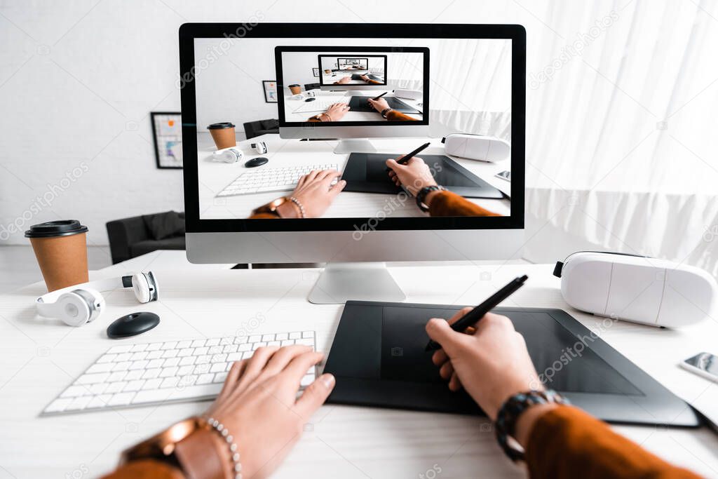 Cropped view of 3d artist using graphics tablet and computer near digital devices on table 