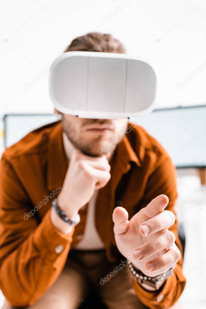 Selective focus of 3d artist in vr headset gesturing on white background