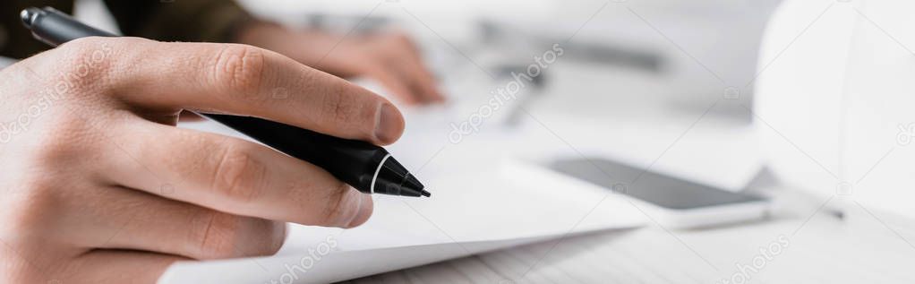 Cropped view of 3d artist holding stylus of graphics tablet near paper on table, panoramic shot 