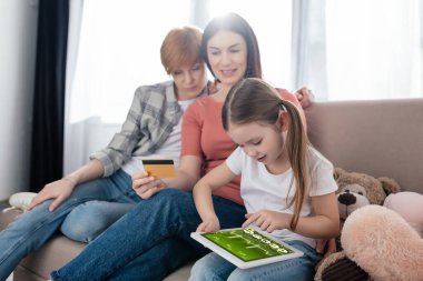 Ekranda e-sağlık uygulaması olan dijital tablet kullanan çocuk, kredi kartı olan aynı cinsiyetten ebeveynlerin yanında 
