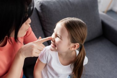 Anne evdeki kanepede gülümseyen kızının burnuna dokunuyor. 