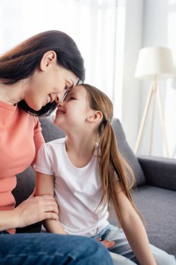 Gülümseyen anne evdeki kanepede mutlu kızına bakıyor. 