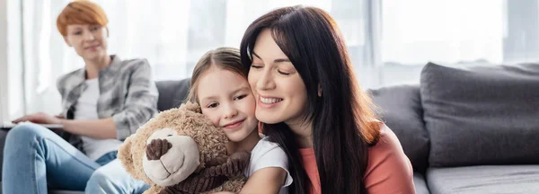 Selective Focus Smiling Mother Hugging Daughter Teddy Bear Parent Couch — Stock Photo, Image
