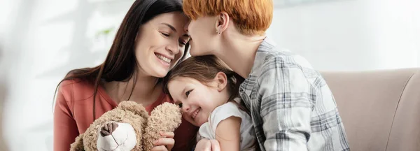 Felici Mamme Che Abbracciano Sorridente Figlia Con Orsacchiotto Sul Divano — Foto Stock