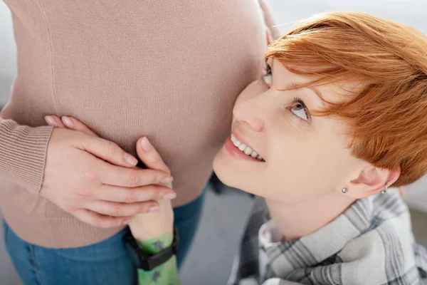 Gülümseyen Kadın Gri Arka Planda Hamile Kız Arkadaşının Elini Tutuyor — Stok fotoğraf
