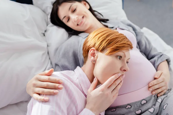 Shocked Woman Listening Belly Smiling Pregnant Girlfriend Bed — Stock Photo, Image