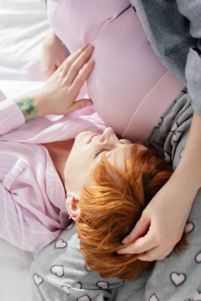 Gülümseyen Kadın Yatakta Yatarken Hamile Kız Arkadaşının Karnına Dokunuyor — Stok fotoğraf