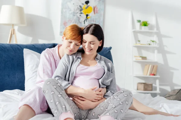 Gülümseyen Kadın Yatakta Hamile Kız Arkadaşını Kucaklıyor — Stok fotoğraf