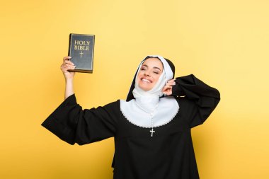 Güzel, neşeli bir rahibe kutsal incili gri üzerinde tutuyor.