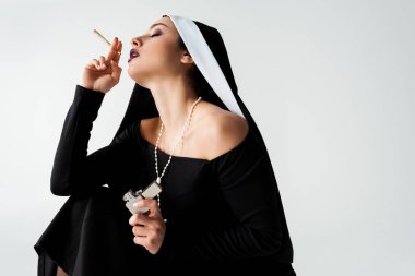 passionate nun smoking marijuana joint with lighter isolated on grey clipart
