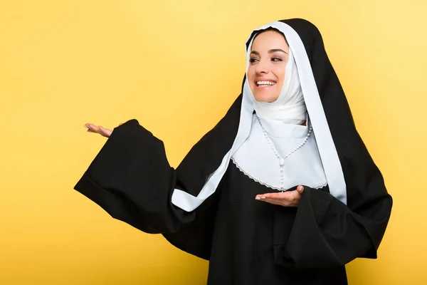 Schöne Fröhliche Nonne Präsentiert Etwas Auf Gelb — Stockfoto