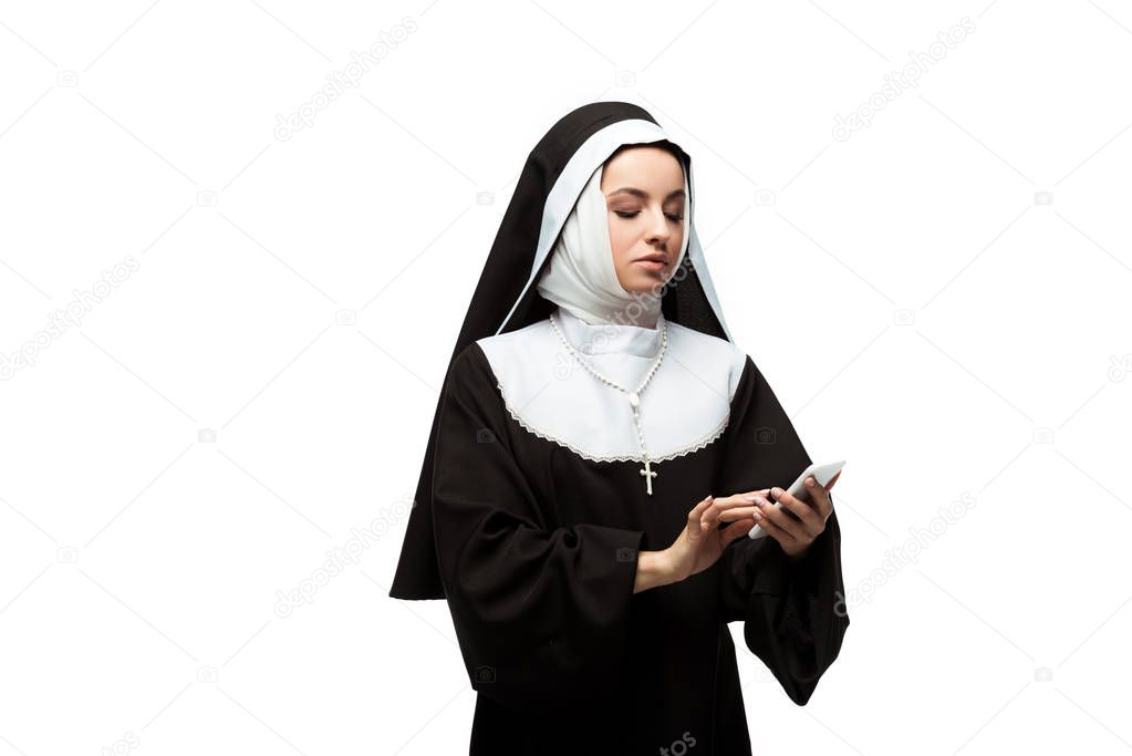 serious nun using smartphone isolated on white