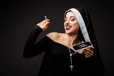 happy nun holding dollar banknote and smartphone with cocaine lines isolated on grey clipart