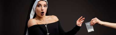 panoramic shot of surprised sexy nun taking plastic bag with cocaine isolated on grey clipart