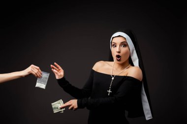 shocked sexy nun with money buying plastic bag of cocaine isolated on grey clipart
