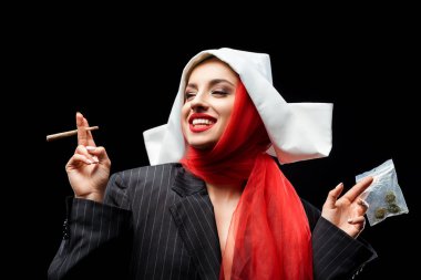 excited nun holding marijuana joint and buds isolated on black clipart