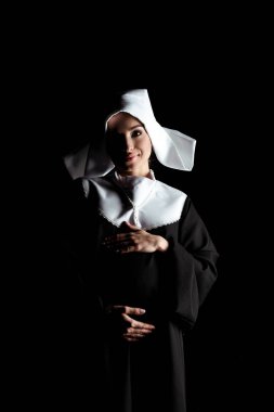 young happy pregnant nun touching tummy isolated on black clipart