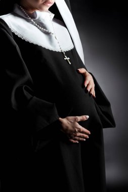cropped view of pregnant nun touching tummy on grey clipart