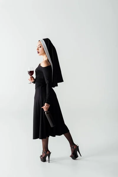 Attraktive Sinnliche Nonne Mit Glas Und Flasche Wein Auf Grau — Stockfoto