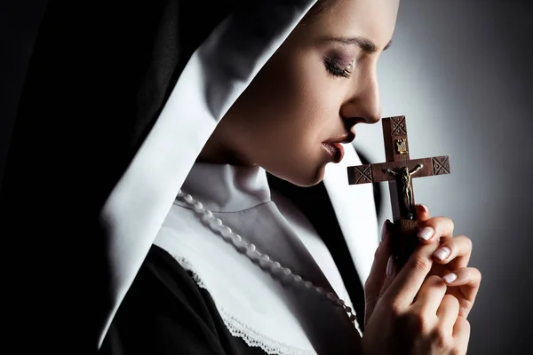 悲伤的年轻修女在灰十字架上祈祷 — 图库照片