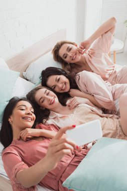 Bekarlığa veda partisinde yatakta yatarken arkadaşlarıyla selfie çeken Afrikalı Amerikalı kızın seçici odağı.